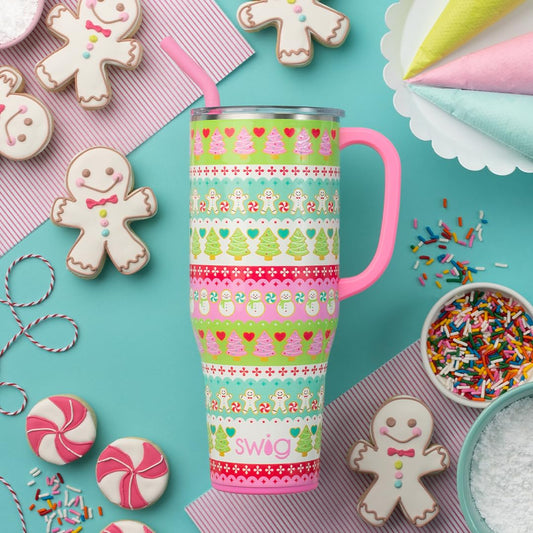 Colorful tumbler with gingerbread design surrounded by cookies and sprinkles on a turquoise background